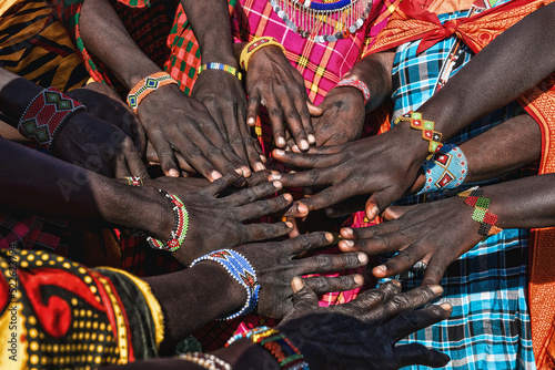 Hands of Maasai Mara tribe people putting together showing their bracelet