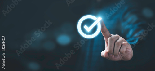 Businessman hand touching glowing correct sign mark with copy space area for document approval and project approve concept.