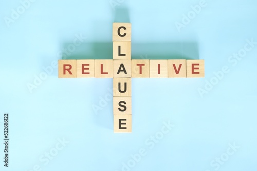 Relative clause concept in English grammar education. Wooden block crossword puzzle flat lay in blue background.