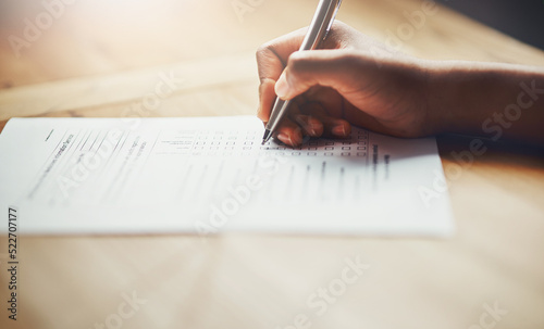 Closeup of business hands of a person filling out paperwork. Hand of an individual writing test, information or survey on paper to complete application or contract form on the desk at work.