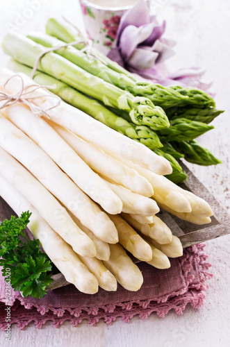 Fresh raw green and white asparagus bundle offered as close-up on wooden shabby chic tray