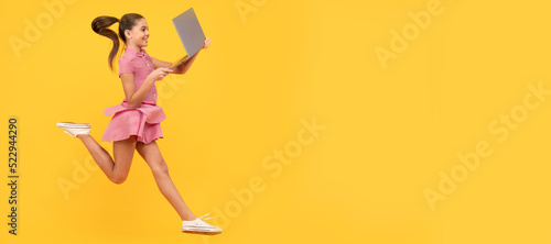 happy girl hurry up running using notebook to find sale and discount, copy space, shopping online. School girl portrait with laptop, horizontal poster. Banner header with copy space.