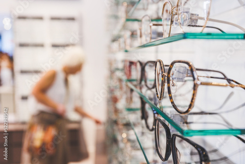Glasses shop. Eyeglasses or spectacles, vision eyewear, with lenses. Customer choosing glasses in background