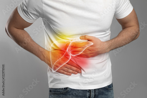 Man suffering from liver pain on grey background, closeup