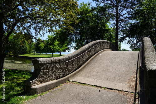 Stone bridge arches over a river through a community park