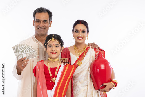 Bengali family in traditional clothing holding 500 rupees banknotes and piggy bank 