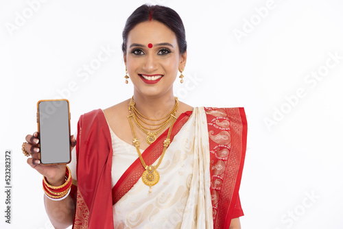 Happy bengali woman in traditional sari showing mobile phone screen 