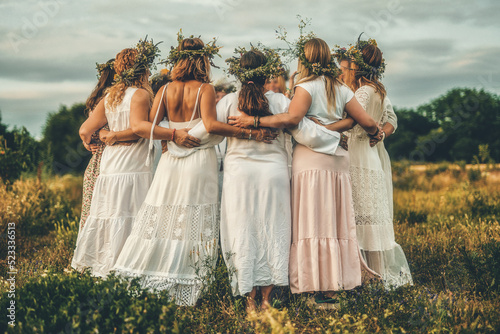 Women in flower wreath on sunny meadow, Floral crown, symbol of summer solstice.