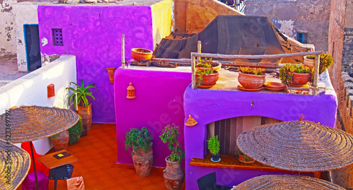 Essaouira, Morocco - September 9. 2011: Colorful purple moroccan style riad roof top restaurant terrace, umbrellas, tables