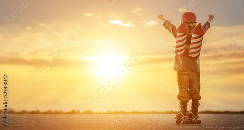 Little boy in a rocketman costume on roller skates at sunset. Ñhild imagines himself as a superhero and dreams of flying in a backpack with rockets.