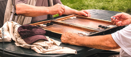 Board game of backgammon.Two old adult men playing backgammon in the street,hobby