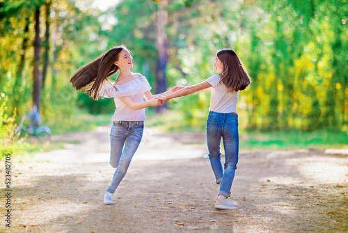 Two girls spinning holding hands, walking in the summer forest