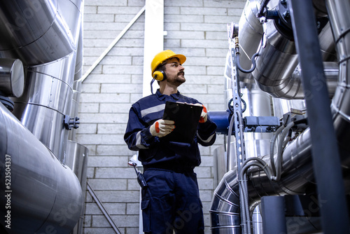 Worker checking pipes in city heating plant.