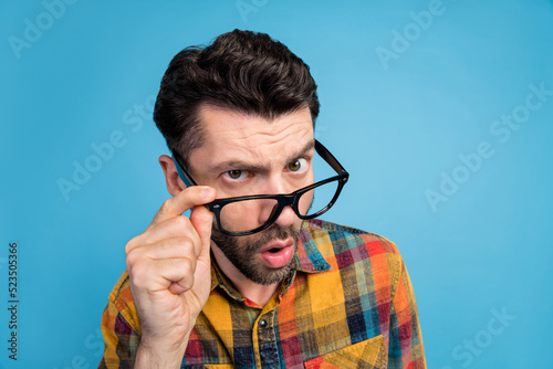 Photo of suspicious questioned handsome guy dressed plaid shirt arm touching eyeglasses unexpected news isolated on blue color background