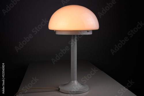 modern desk lamp with mushroom shape spaceage vintage midcentury design front side view white black background with warm orange light isolated in the studio living room creative HIGH RESOLUTION