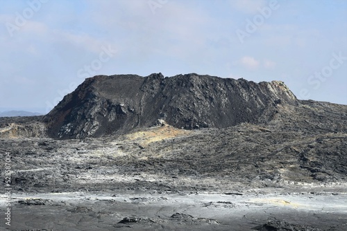 The main vent from the Fagradalsfjall 2021 eruption, Iceland, taken one year later. Mineral deposits can be seen on the lava field in front. Volcanic crater with lava field in the foreground.