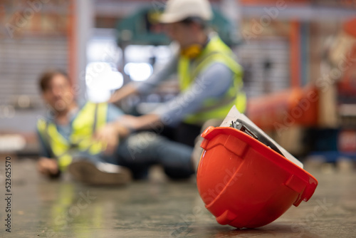 Close Up on Red Hard Hat with Blurred Injured Factory Workers as a Background