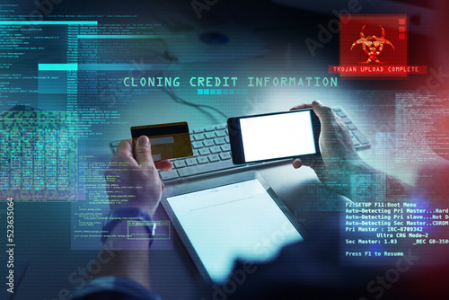 Cyber security, hacking and fraud with a computer hacker holding a credit card and phone while cloning a bank account. Theft, crime and data protection with CGI, special effects or overlay background