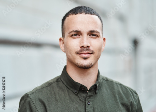 Closeup face of a serious, motivated and ambitious man standing outside in a city, town or downtown alone. Portrait, headshot and face of social worker or volunteer looking forward with trust or care