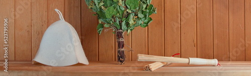 Photo with a composition of sauna items. Traditional felt hat, Birch broom and massage Sticks. Wooden Background. Web Banner. Sauna Conception.