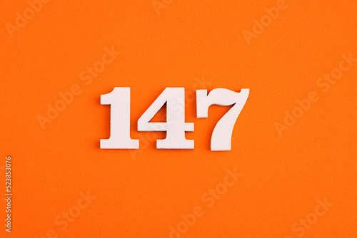 White wooden number 147 on eva rubber orange background