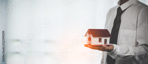 Business person hands holding home model, small building red house. Real estate agents offer contracts to purchase or rent residential. Mortgage property insurance moving home and real estate concept