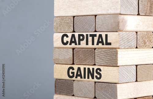 The text on the wooden blocks CAPITAL GAINS