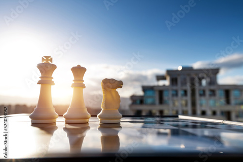 Chess king, queen and knight on city background