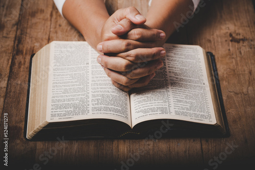 Close up of christian woman hand on holy bible are pray and worship for thank god in church with black background, concept for faith, spirituality and religion