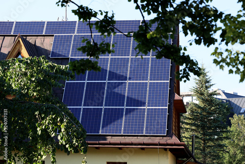 Panele solarne na skośnym dachu budynku mieszkalnego.