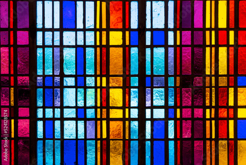 Colorful stained glass window in modern design with blue, red, violet and yellow pieces of glass