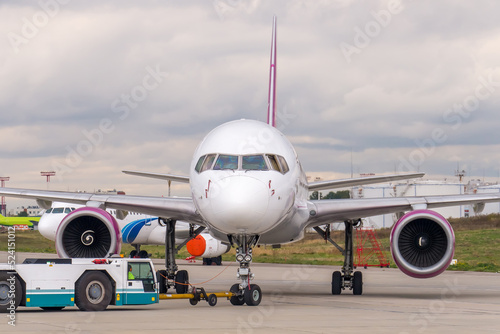 Pushback passenger jet aircraft procedure. Low-profile vehicle called pushback tractor or tug moves the aircraft along the airport apron