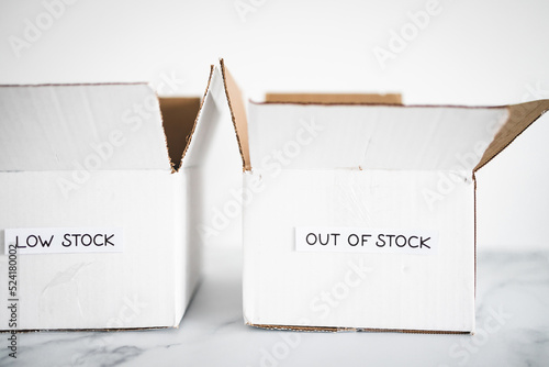 Low stock and out of stock texts on white delivery parcels on white background, supply chain shortages and delays after the covid-19 global pandemic