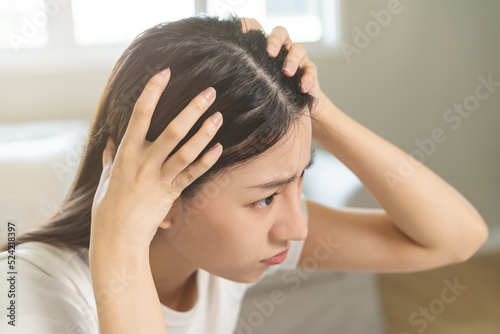 Damaged hair, face serious asian young woman, girl worry looking at scalp in mirror, hand in break into front hair loss, thin problem symptom from shampoo at home. Health care of beauty concept.