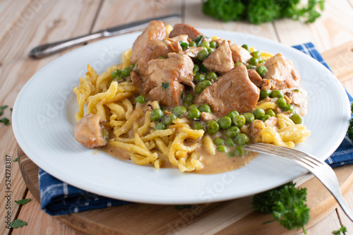 Turkey goulash with cream sauce, german spaetzle noodles and green peas on a plate