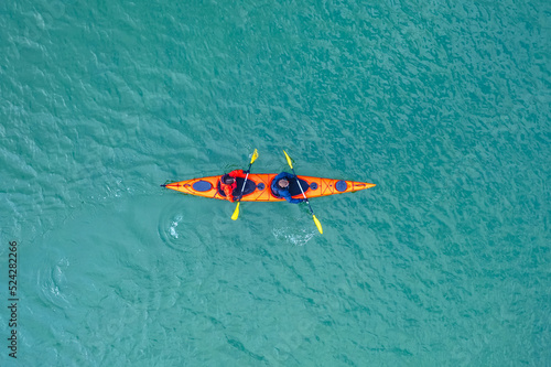 Red kayak boat two rowers on blue turquoise water sea, sunny day. Concept teamwork for business plan, aerial top view