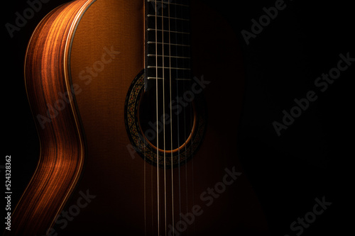 Classical guitar close up, dramatically lit on a black background with copy space