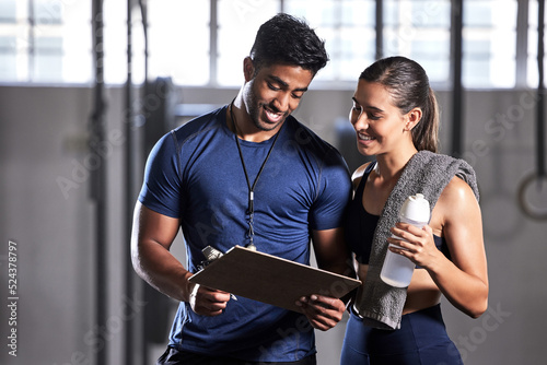 Gym subscription, personal trainer and happy client talking and ready to fill in a membership form. Fitness coach discussing training, workout plan and progress in a health and wellness facility