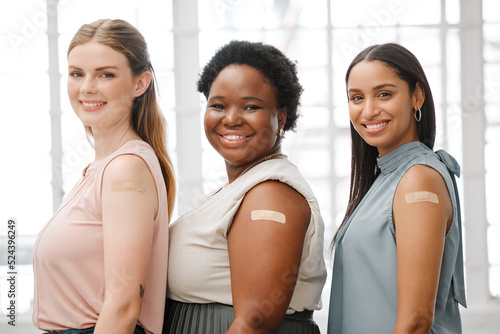 Businesswoman with plaster after vaccination for business covid vaccine, safety and health protocol, protection against the virus. Smiling faces of female coworker standing together, showing support