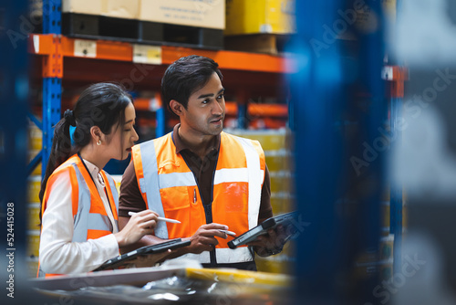 Warehouse worker and manager checks stock and inventory with using digital tablet computer in the retail warehouse full of shelves with goods. Working in logistics, Distribution center.
