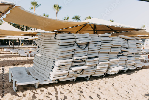 stack of white sunbeds at a beach in the morning