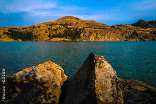 Juniper Bay Beach of Kalamalka lake at sunrise with the view of Mountain Sandberg and glacial rocks on the beach in Vernon, British Columbia, Canada