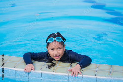 little girl smiling wearing swimming glasses in swimming pool. children playing in swimming pool on summer.
