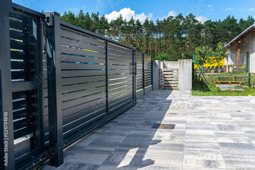 Modern panel fencing in anthracite color, visible sliding gate to the garage as well as a handle and a lock.