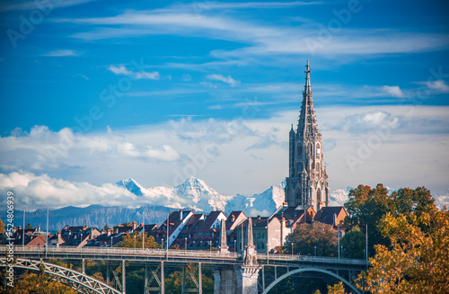 Scenic view of tower of Munster cathedral in Bern, Switzerland. Snowcaped alpine peaks on background. Picturesque sky. UNESCO World Heritage Site