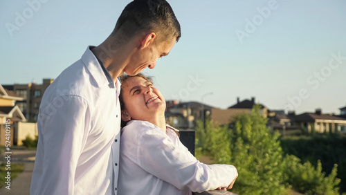 Young man with cerebral palsy comes to stylish disabled woman on bridge. Couple stands on bridge smiling to each other. Sun lights faces of lovers on sunny day