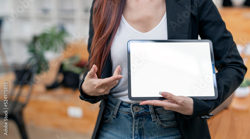 Businesswoman showing blank screen digital tablet, standing in office.