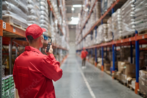 Warehouse worker communicating with his colleague over the walkie-talkie