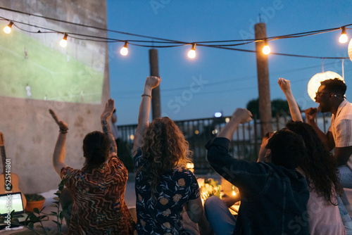 A group of sports fans watches a soccer world championship on the projector.