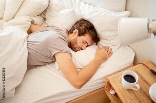 Sleeping, resting and sleepy man lying in bed with his eyes closed in a deep sleep in his bedroom. Rest, relax and tired person at home dreaming and relaxing at his house taking a late morning nap